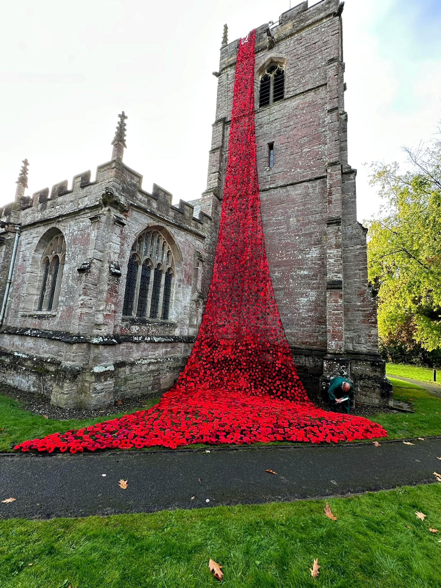 Close up view of the knitted poppies cascading down the bell tower of Inkberrow church