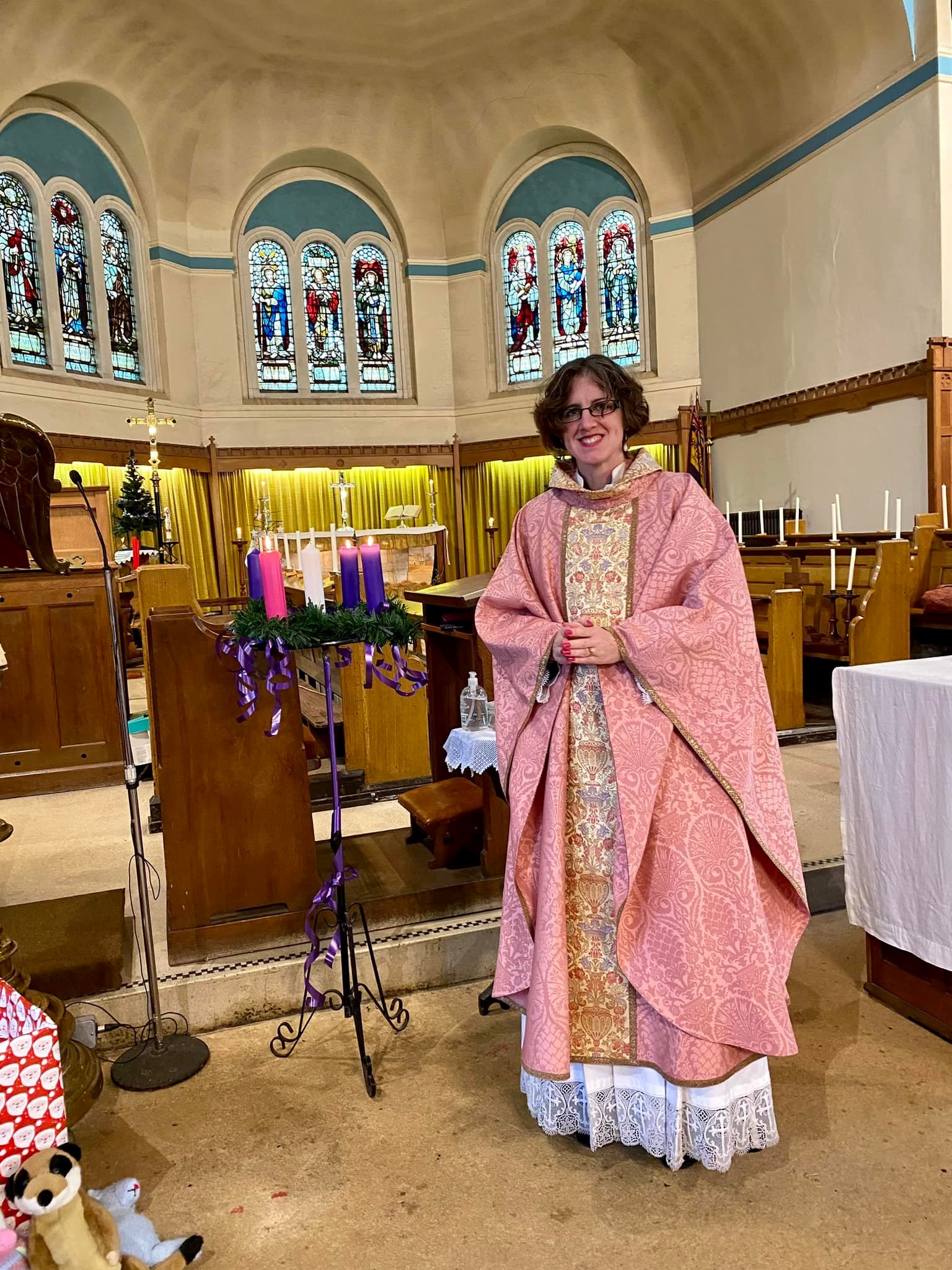 Victoria Barlow in rose-coloured robes next to the advent candle at St Peter's Church in Cradley