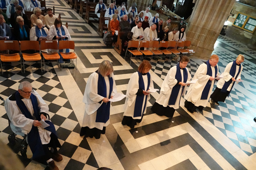 Readers standing at the front of the cathedral facing the altar with the congregation behind