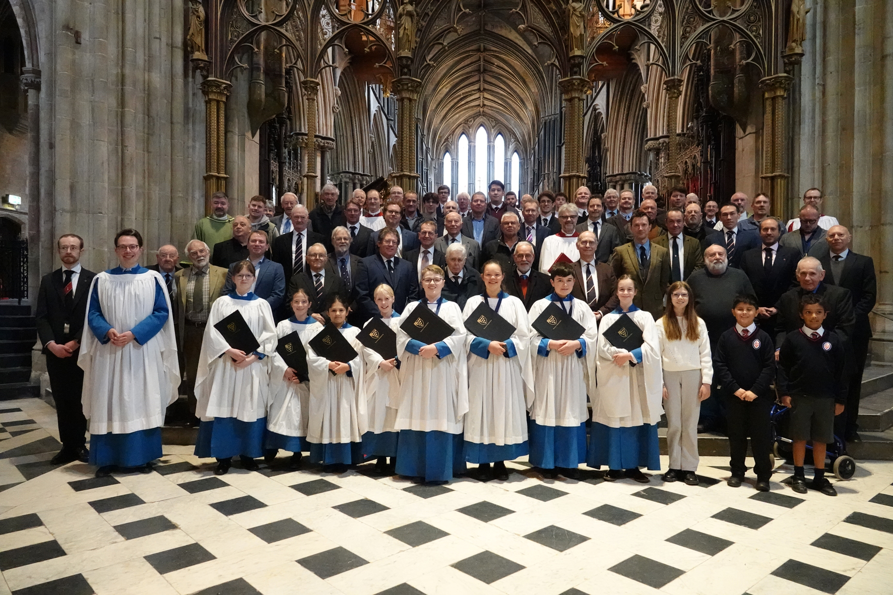 Current and past members of the voluntary choir on the steps to the Quire