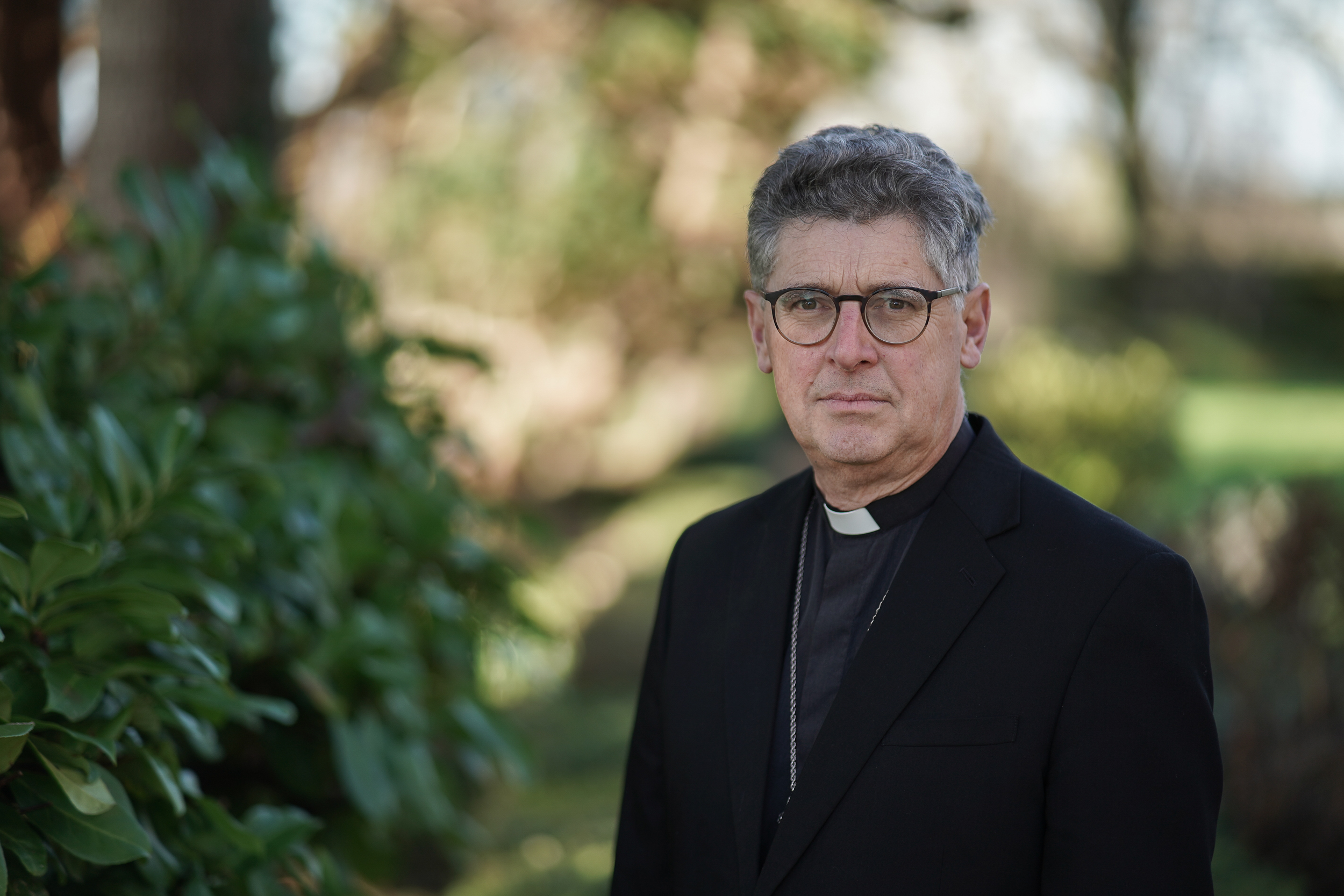 Head and shoulders shot of Bishop Martin in a garden setting with a serious expression