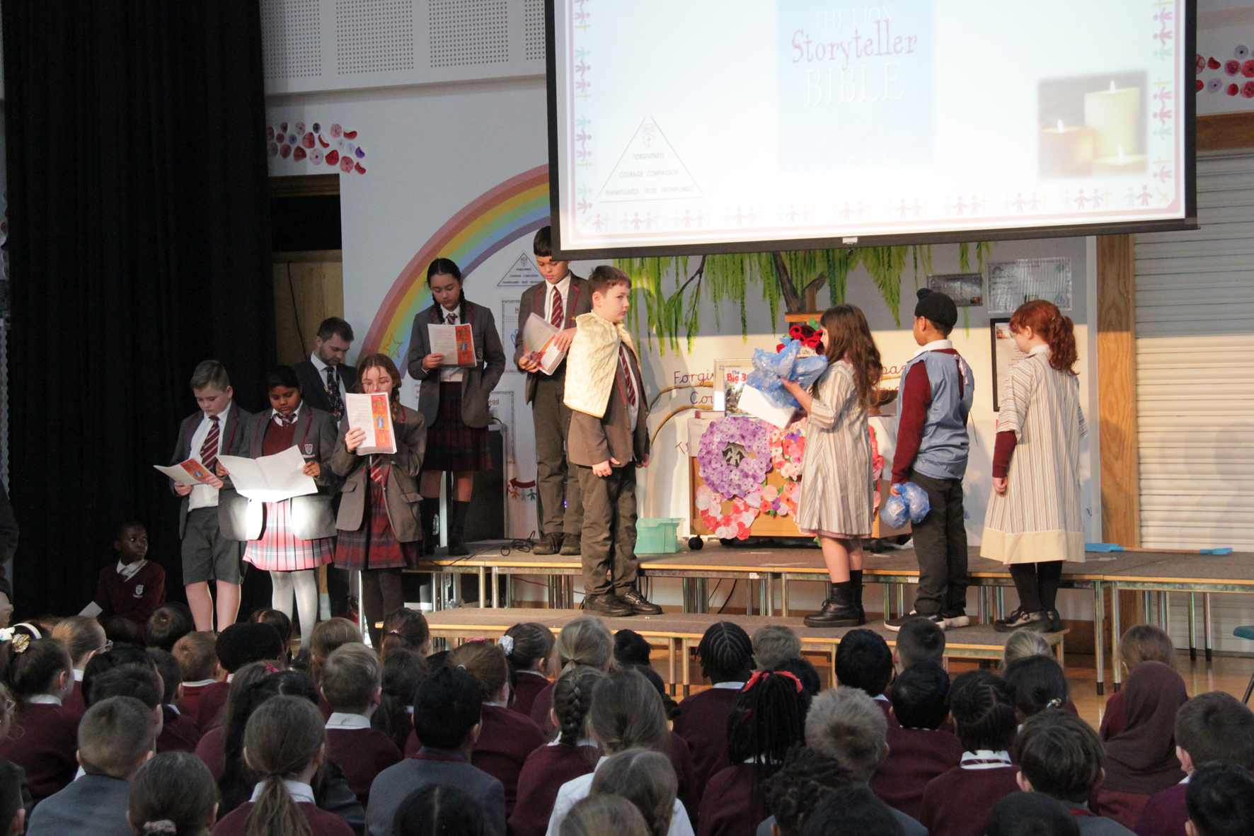 Children on stage acting out a bible story watched by other children sitting on the floor