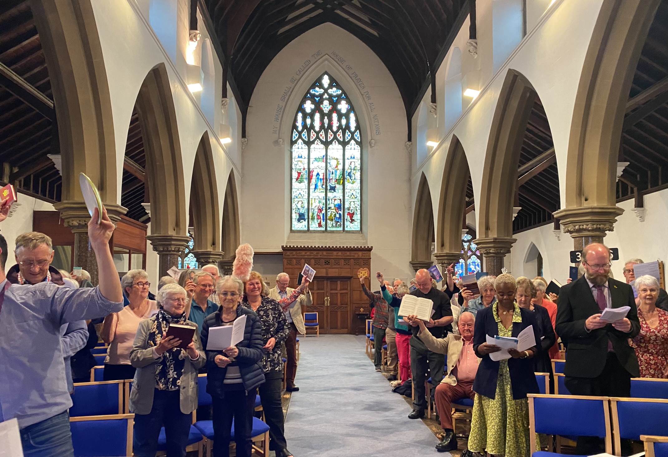 Congregation holding up things that represent their ministry at the service in St Peter's, Bengeworth
