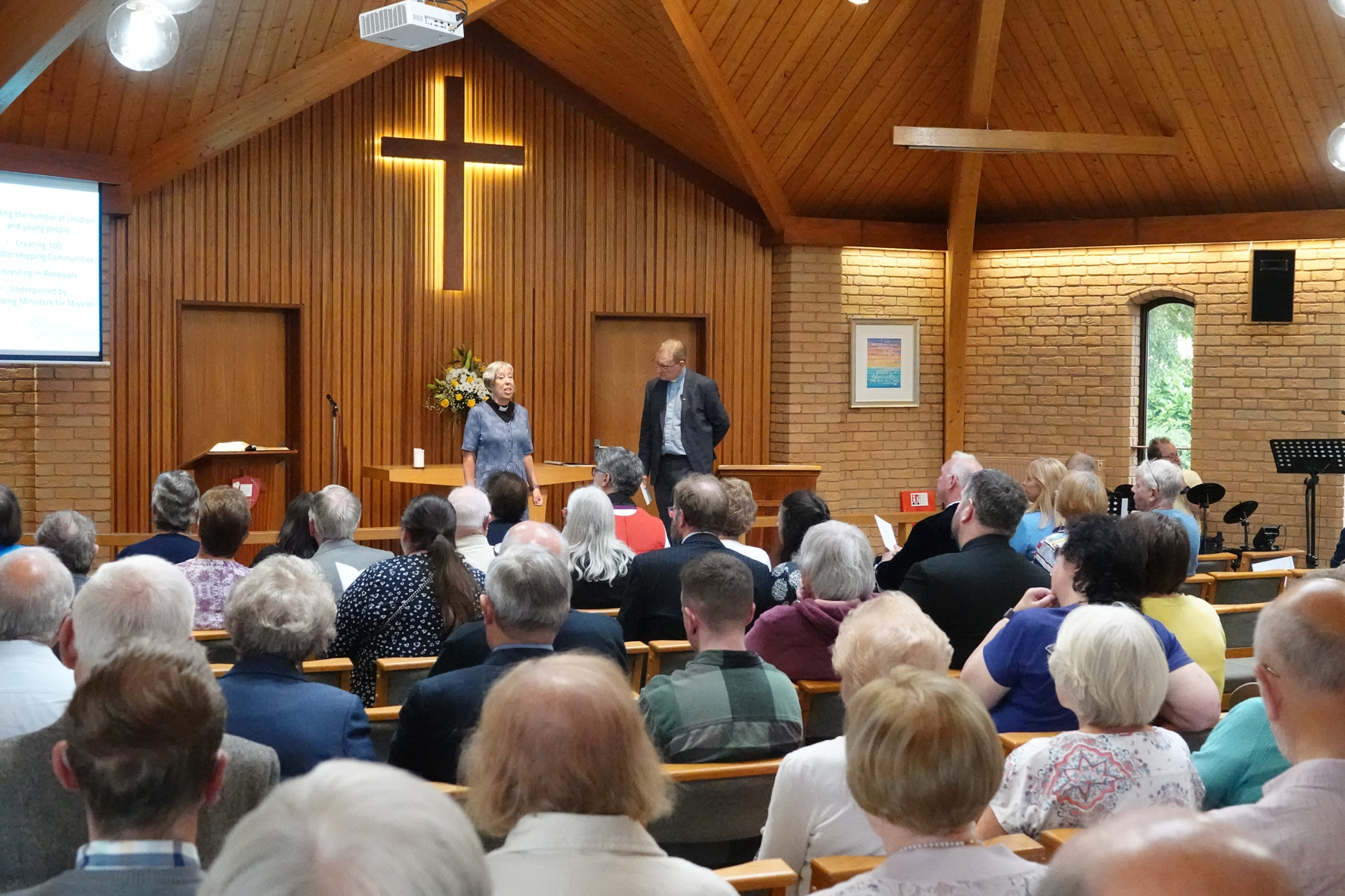 Archdeacon Nikki and Paul Lawlor standing at the front of a packed congregation at St John's Church in Greenlands