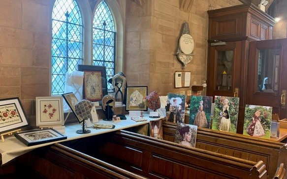 Painted canvases, embroidery and other creations are displayed on church pews at Hallow