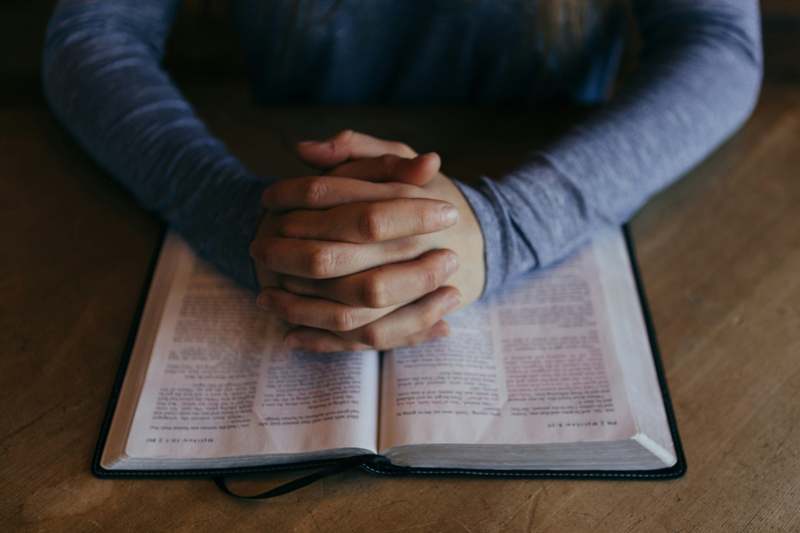 Image of hands in prayer over a bible