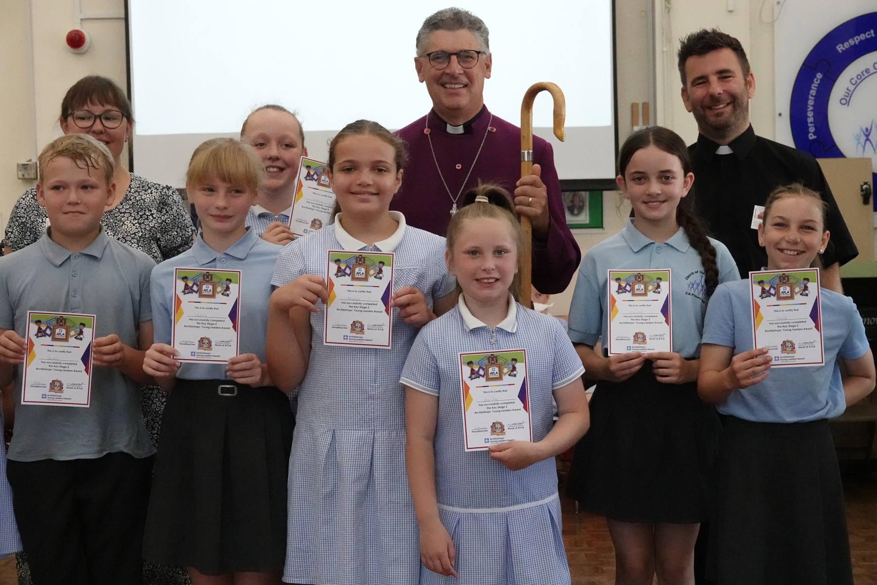 Bishop Martin, Father Chris Smith and Sian Morgan surrounded by school children holding certificates