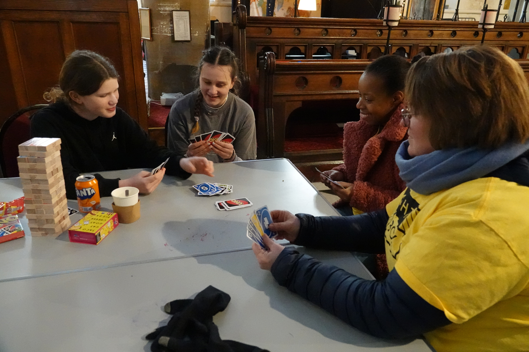 A group of people sitting around a table playing a game of uno