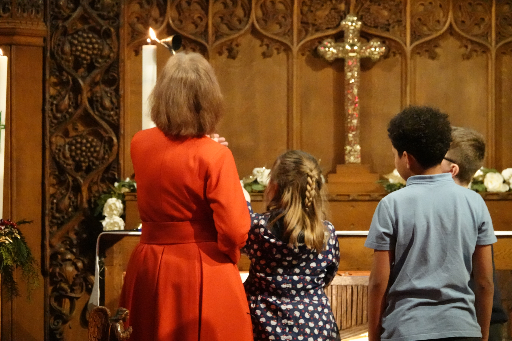 Revd Kalantha helps three children light a tall candle at the front of church
