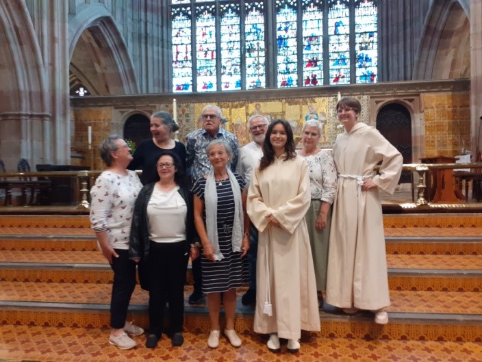 Visitors from the EKM stand on the steps in front of the altar at Malvern Priory