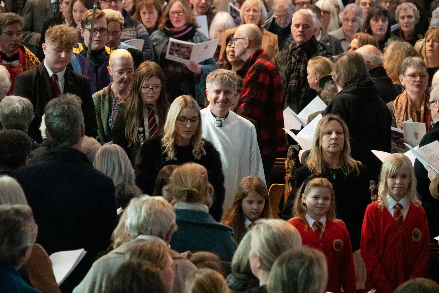 Bishop Hugh walks through a packed cathedral surrounded by children