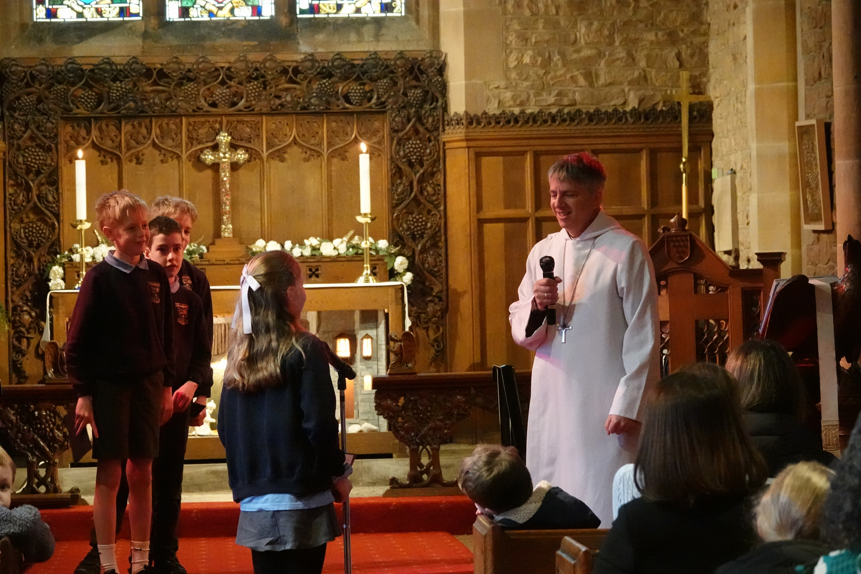 Children ask Bishop Hugh questions standing at the front of Lower Broadheath church