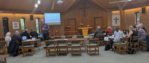 People sitting around tables in a church attending a Cornerstone workshop