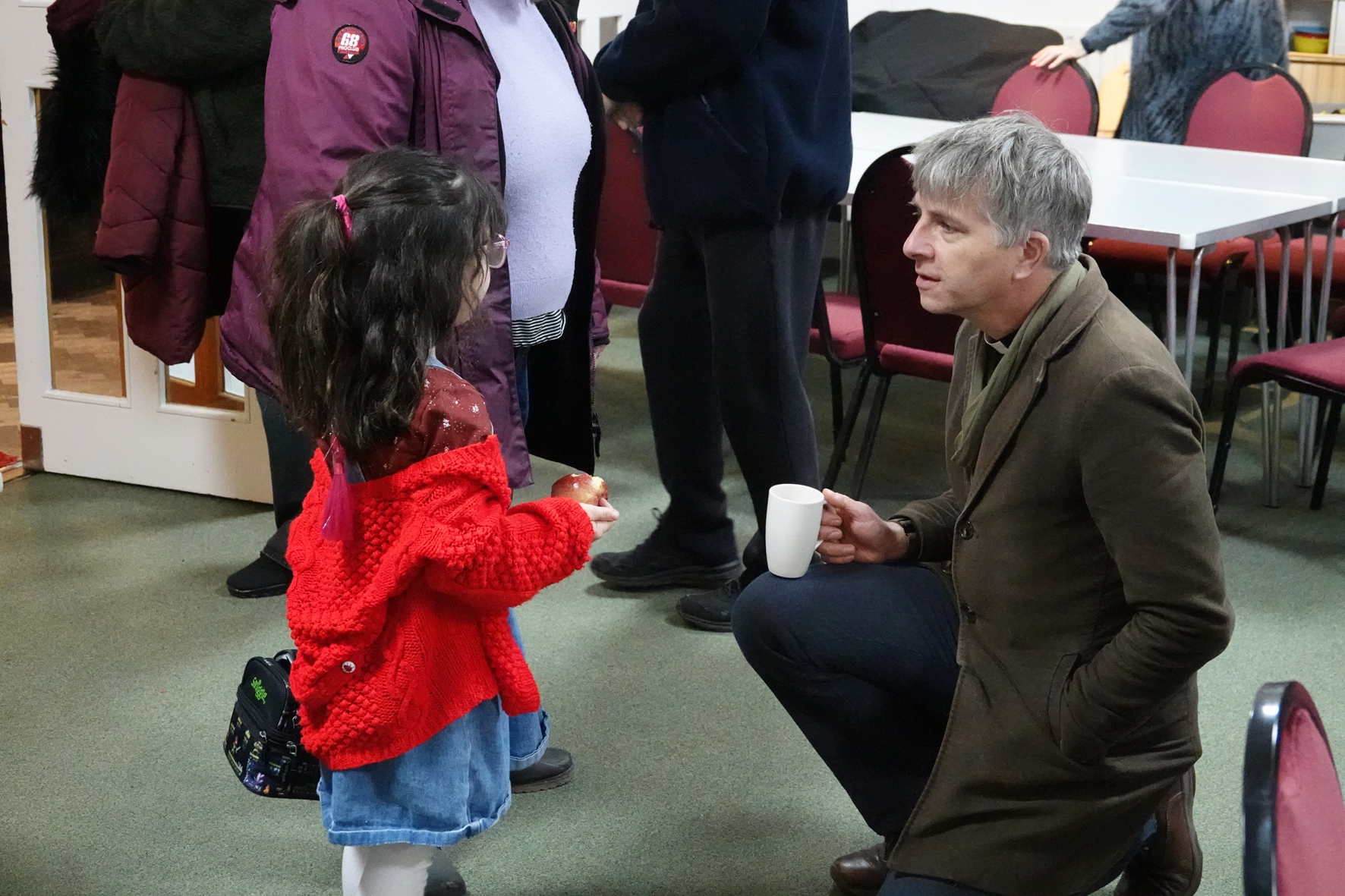 Bishop Hugh crouches down to talk to a young girl