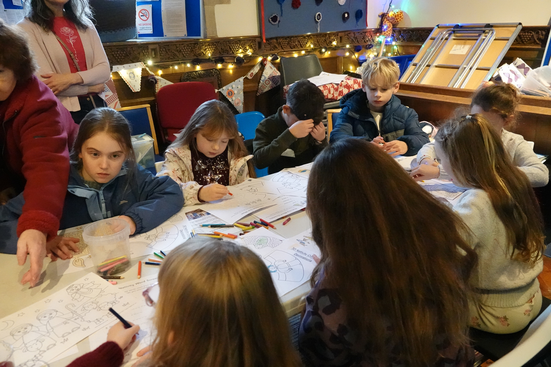 A group of children sat around a table doing some colouring and word searches