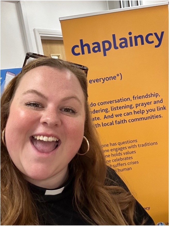 Jess Fellows in front of a sign about chaplaincy