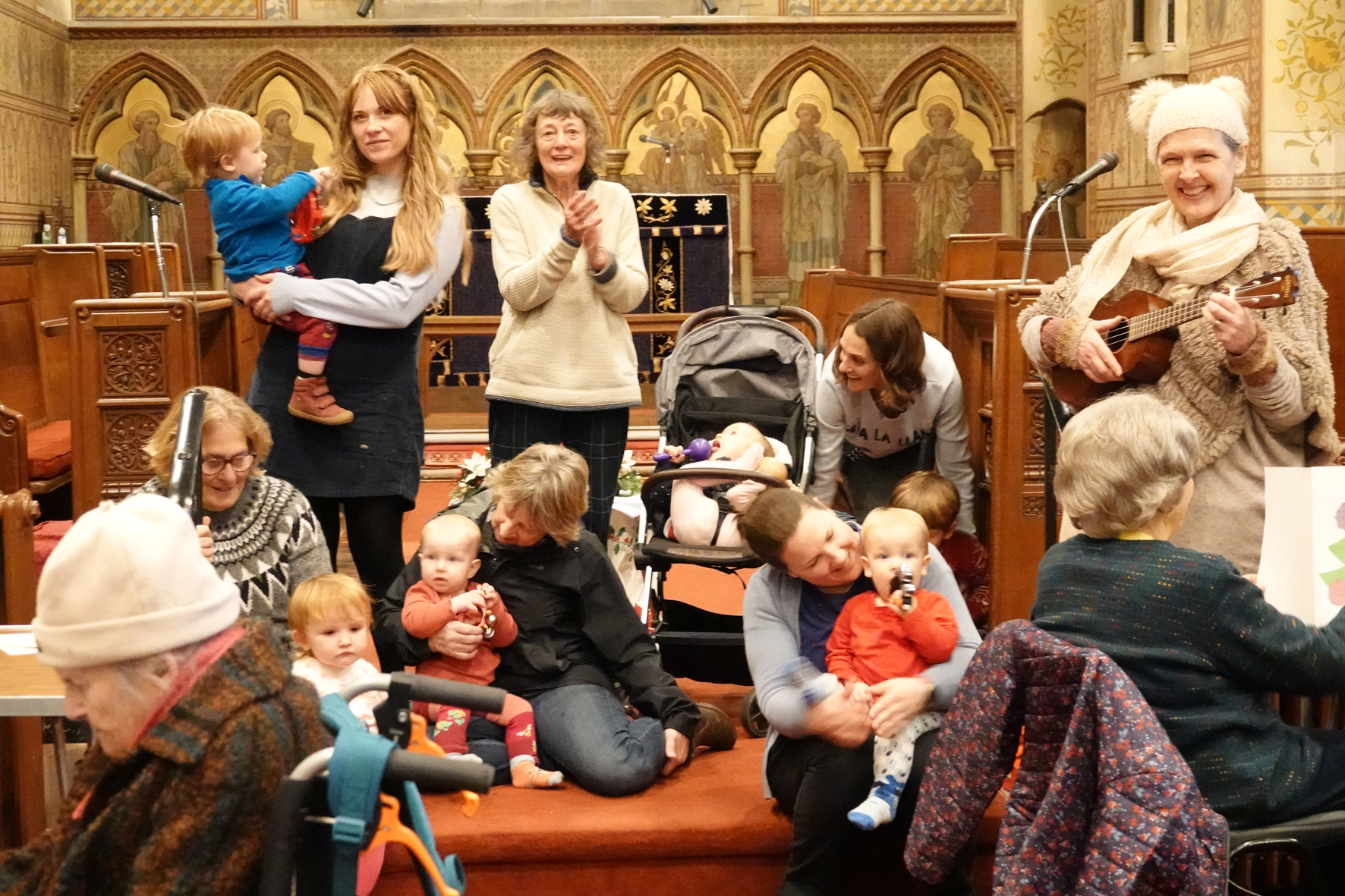 parents and toddlers standing and sitting at the front of Holy Trinity church and singing 