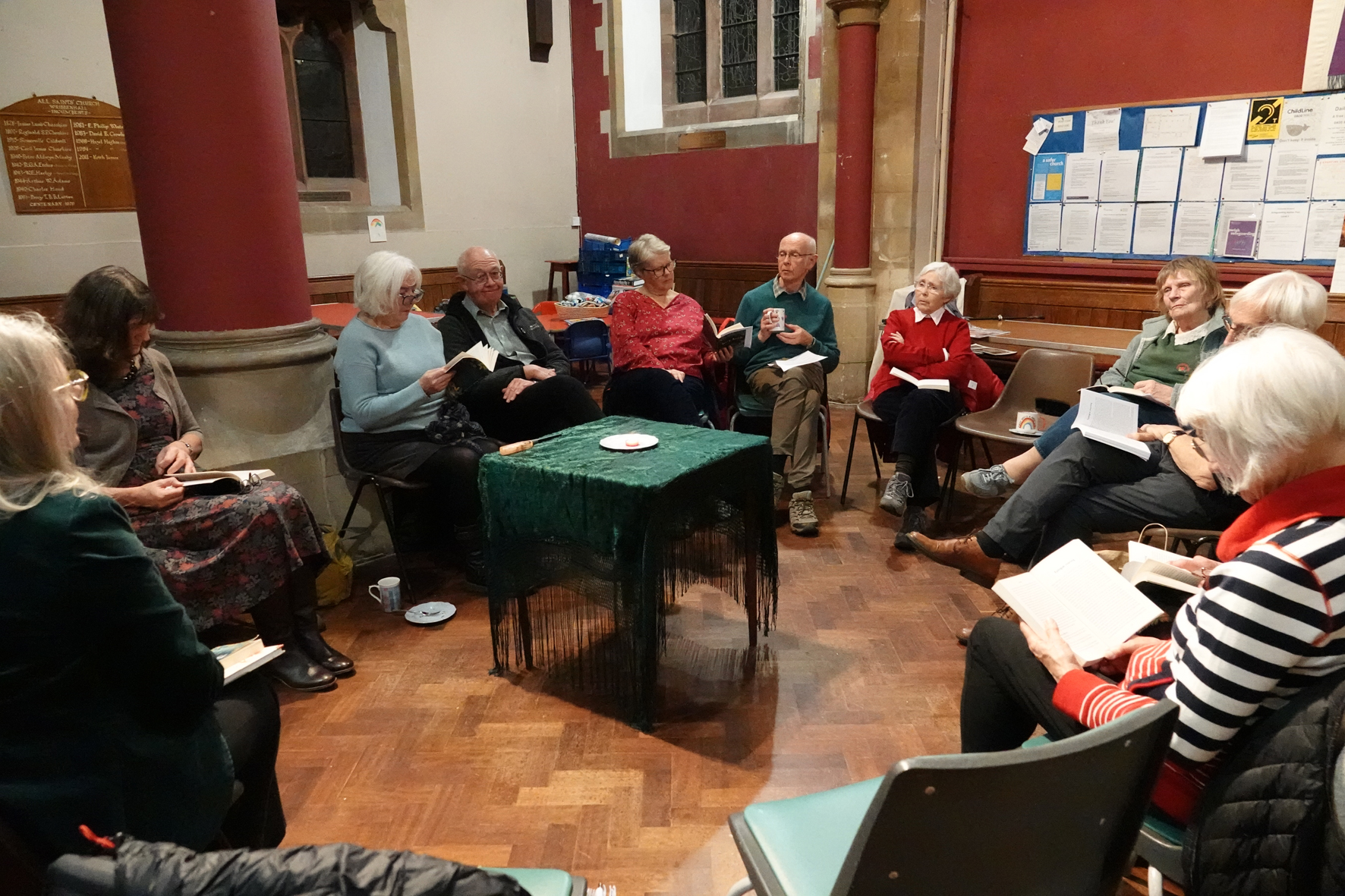 Members of a book club sitting in a circle around a table with the book in their hands