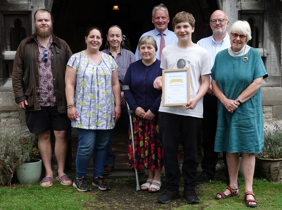 The eco team at Hanley Castle standing outside the church door holding their gold certificate