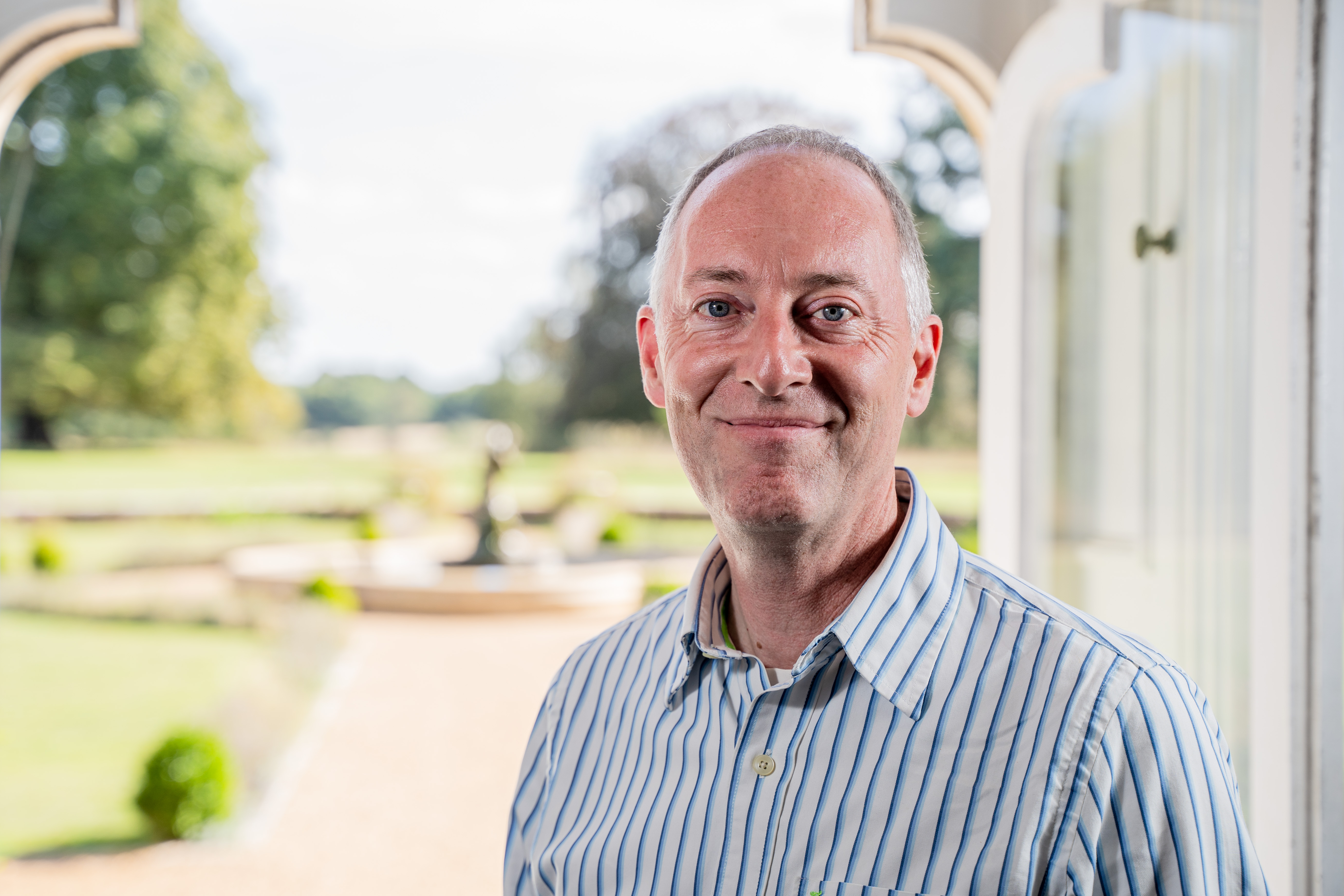 Head and shoulders shot of Andy Todd standing in front of an open door looking out into a garden