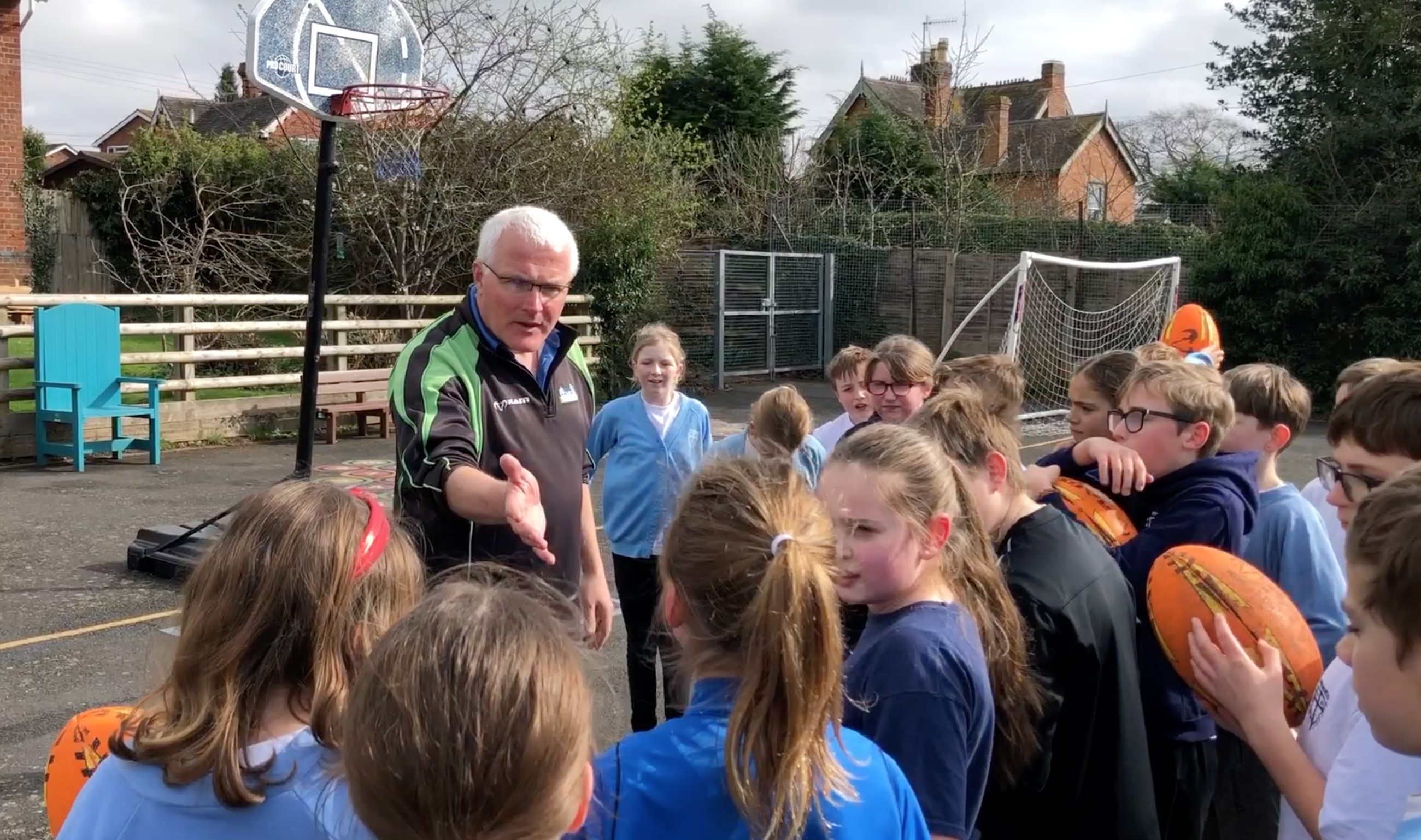 Chris Andrew talking to children in the playground at Broadwas School