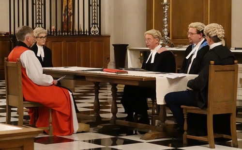 Bishop Hugh sits at a table with four legal representatives as they decide if processes have been properly followed