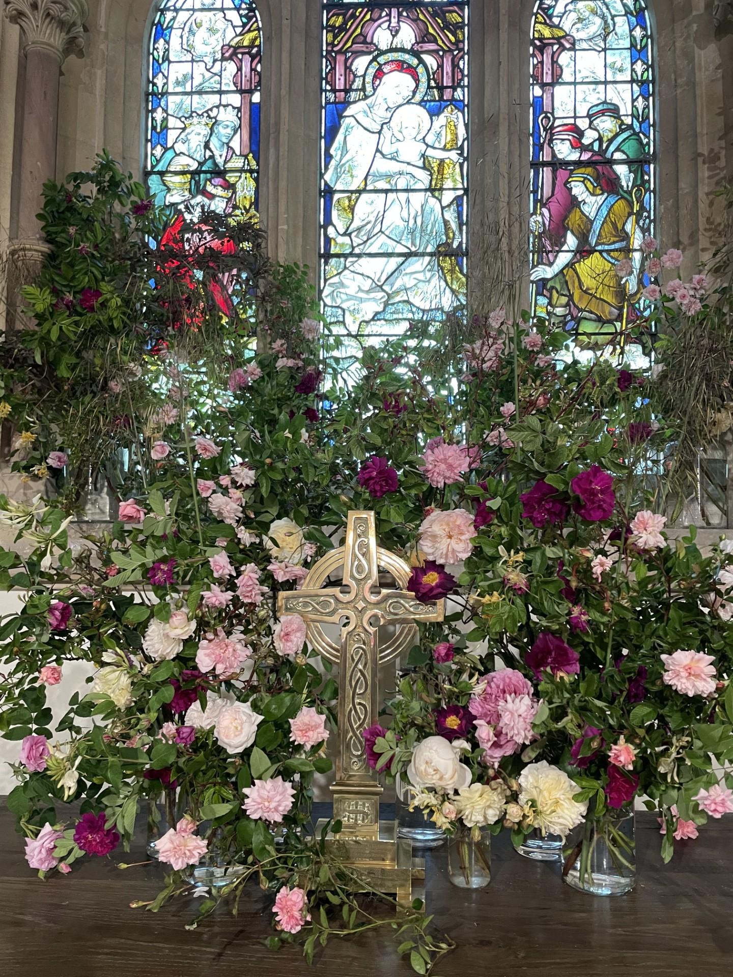 A display of flowers on an altar with a cross in the foreground