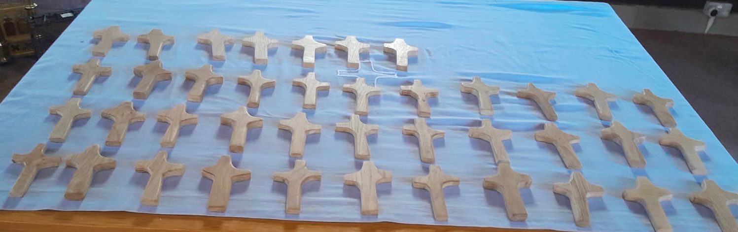 Lots of holding crosses sat in rows on a table/ altar with a table cloth