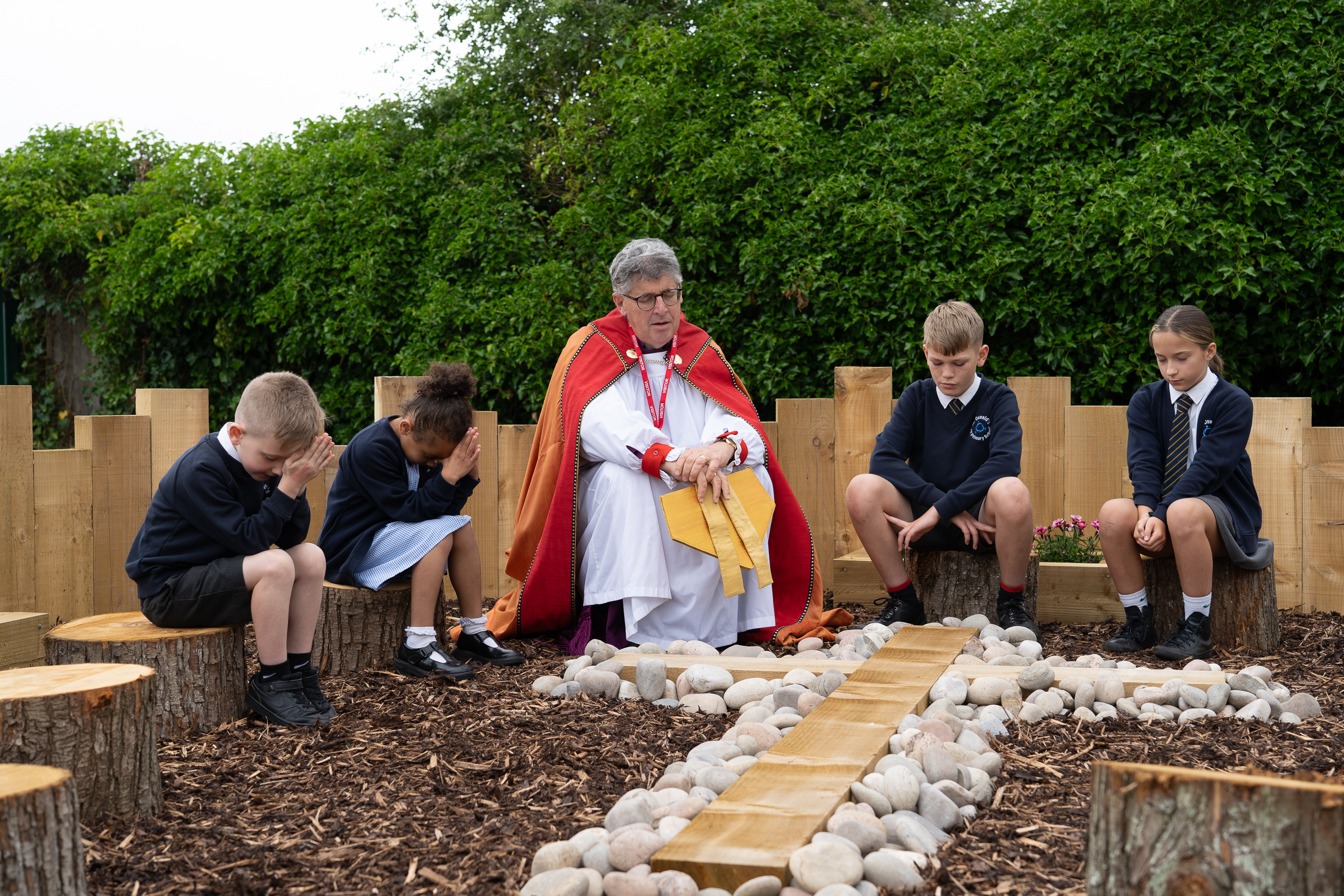 Bishop Martin praying with children in the prayer garden