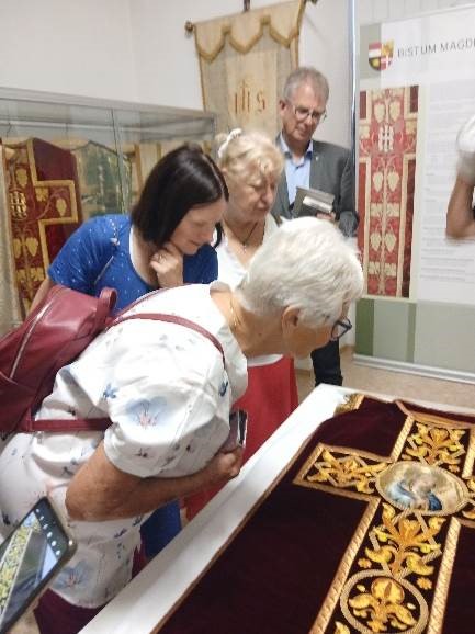 Four people look closely at some vestments