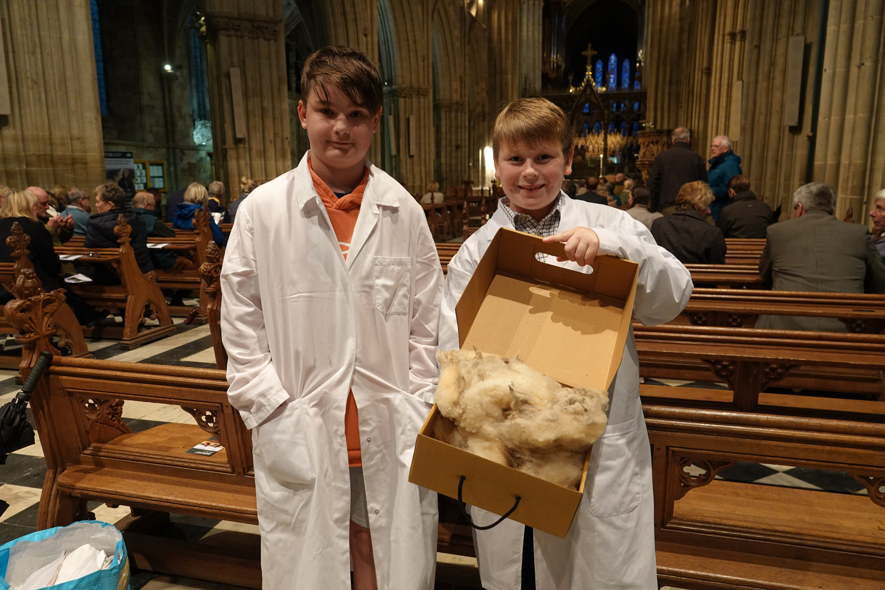 Two boys holding a box of wool in the cathedral