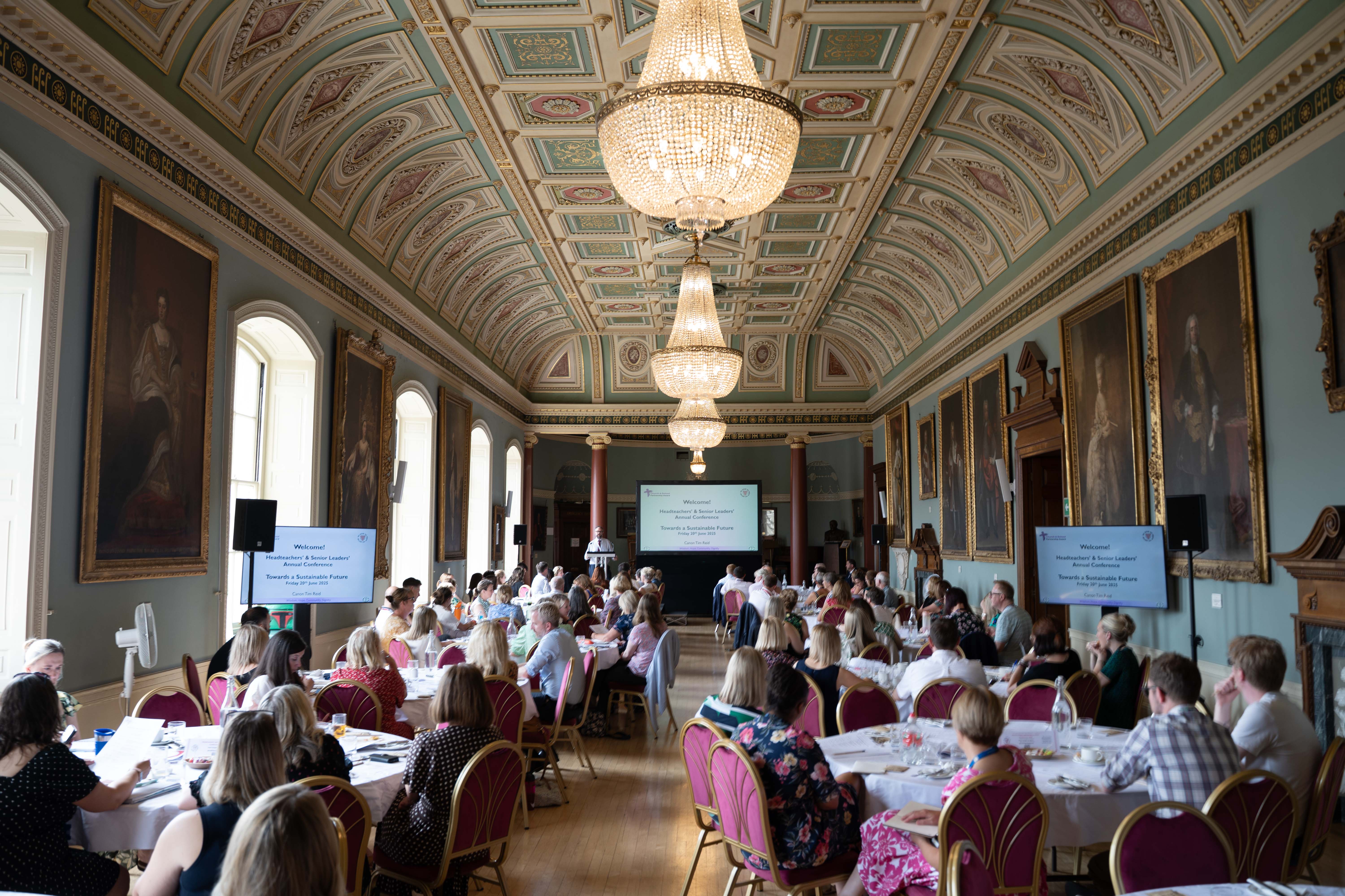 Headteachers sitting around round tables in the Guildhall.