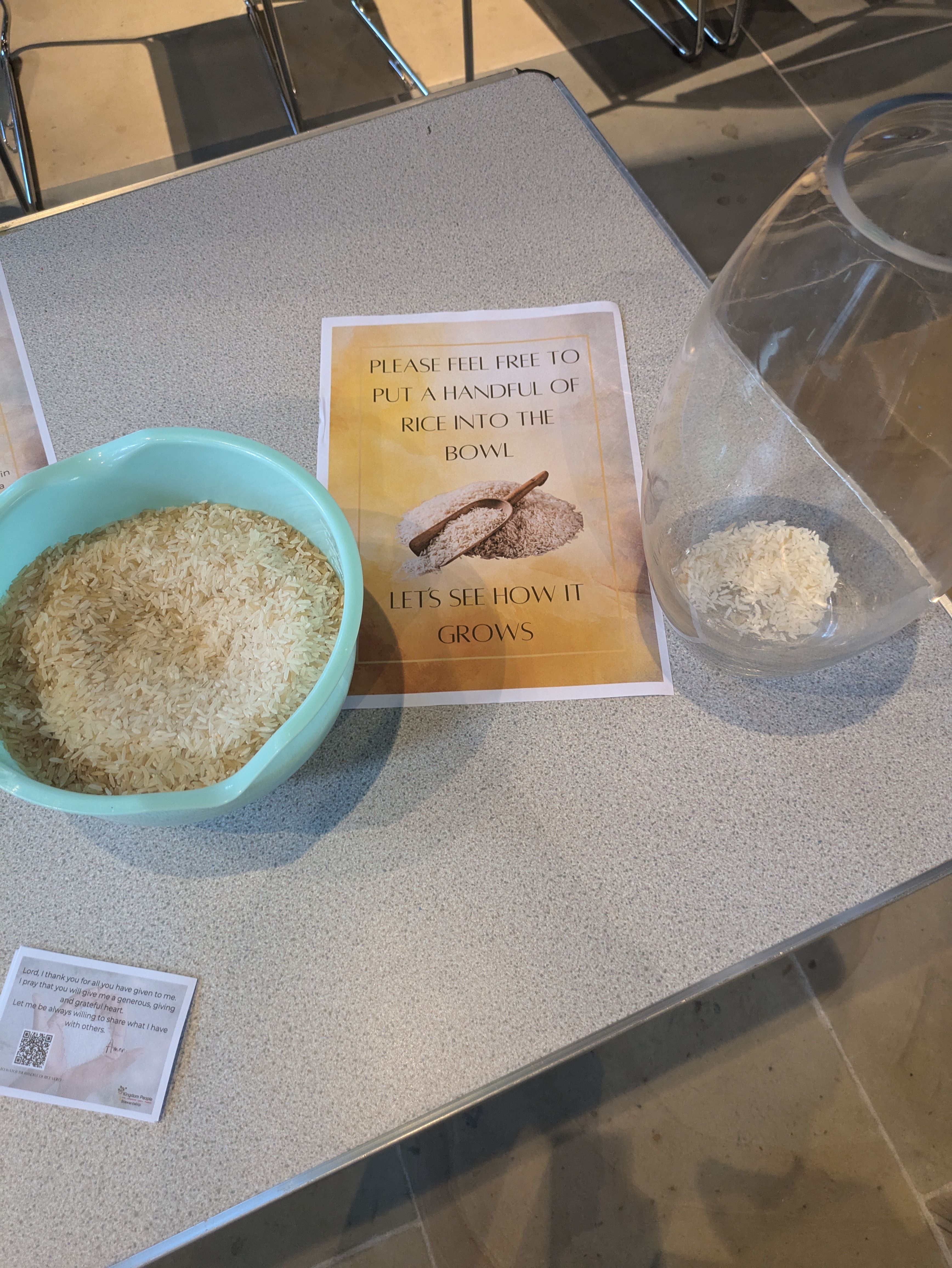 Bowl of rice with a sign to place a handful of rice into a nearby jar.