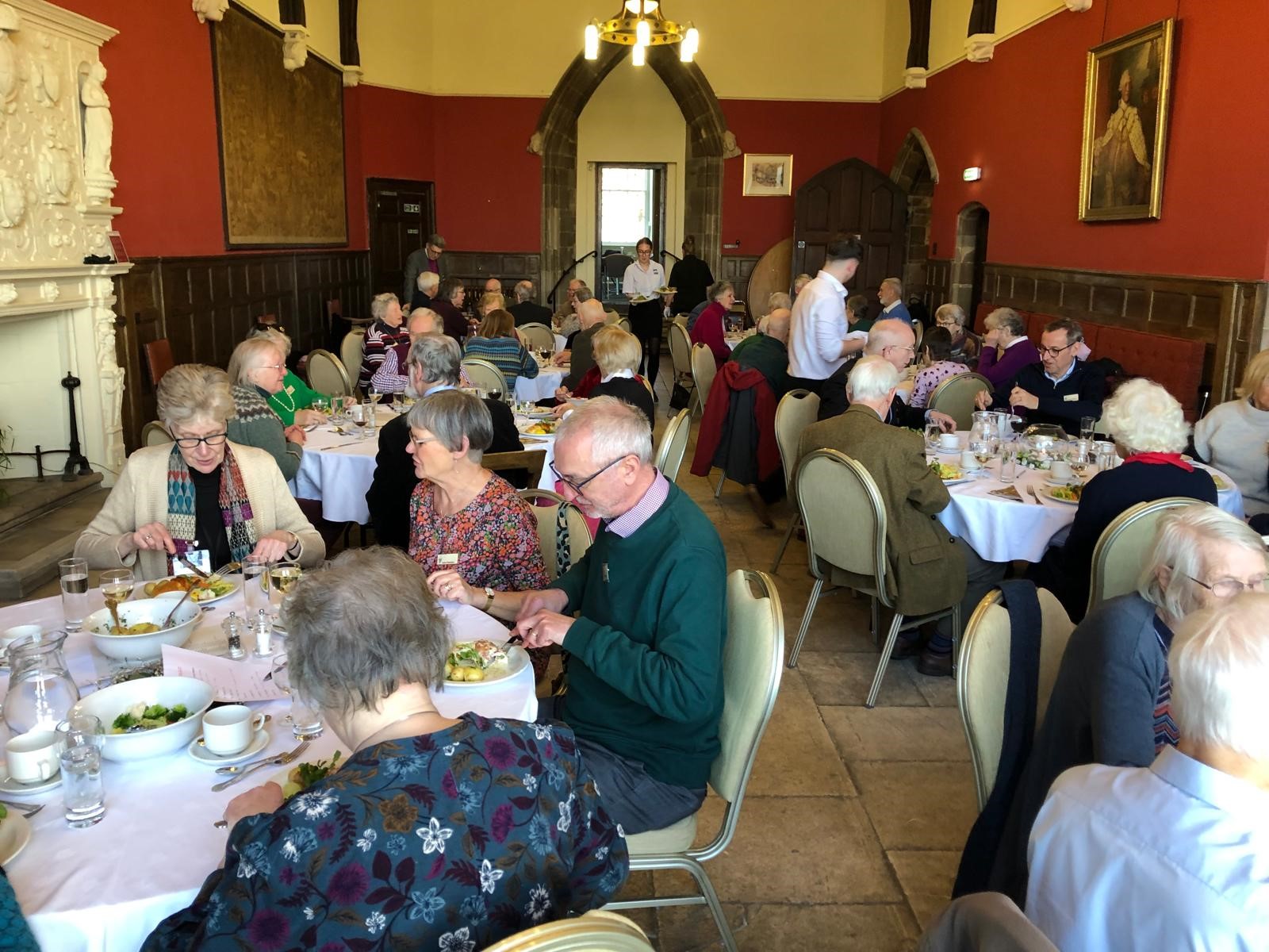 Retired clergy sitting around tables enjoying lunch in the great hall at the Old Palace in Worcester