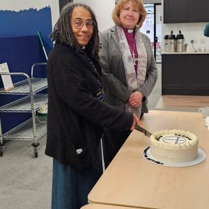 Dr Evie Vernon O'Brien cutting a cake alongside Bishop Anne