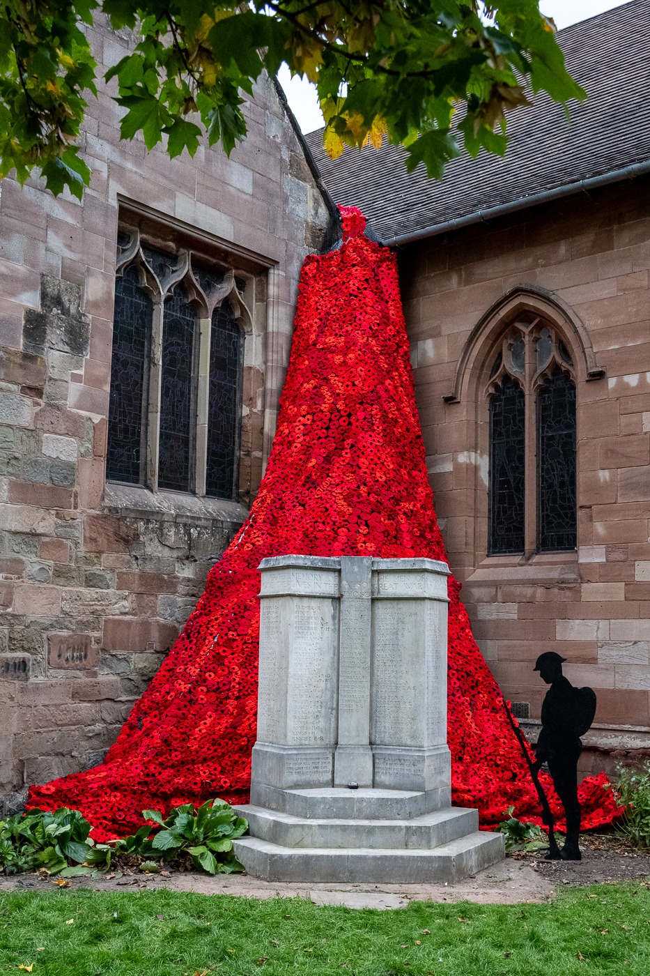 Poppies stretching down from St John in Bedwardine church roof behind the war memorial
