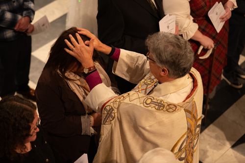 Bishop Martin with his hands on a lady's head as he confirms her.