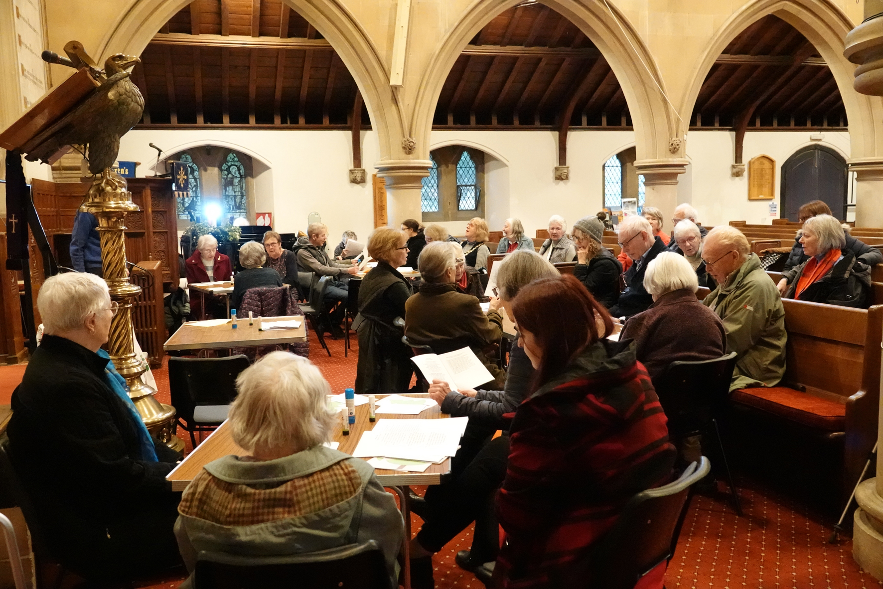 People sitting around tables at the front of Holy Trinity in Malvern