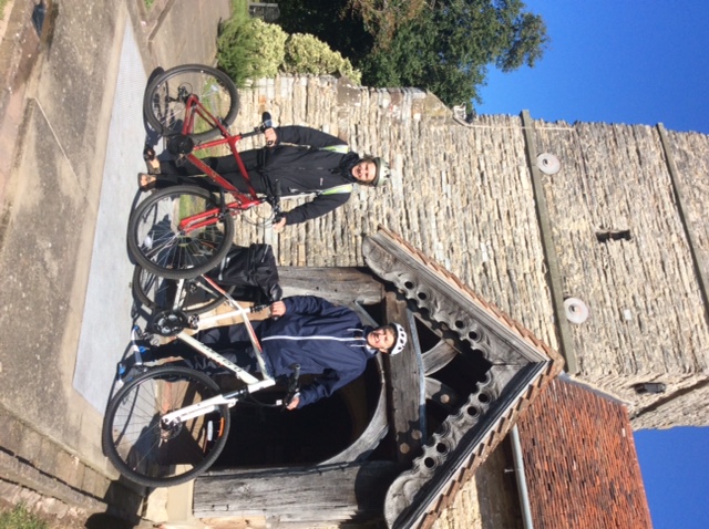 Two people with their bikes stood outside of a church