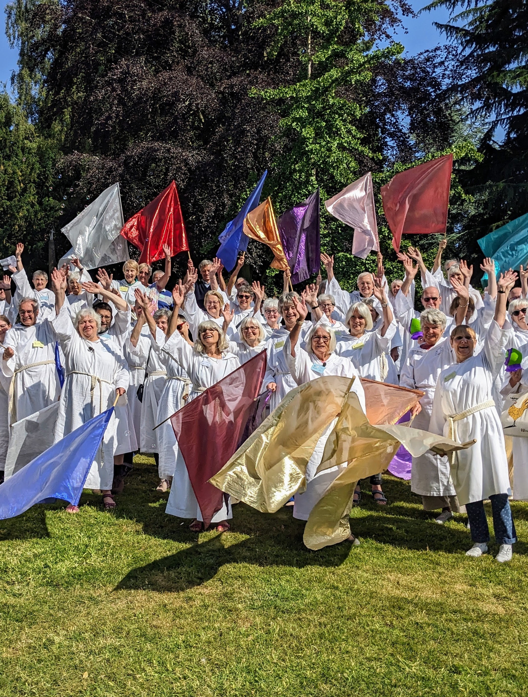 Volunteers at lifepath wearing white cassocks and standing in the grounds of Malvern Priory waving flags 