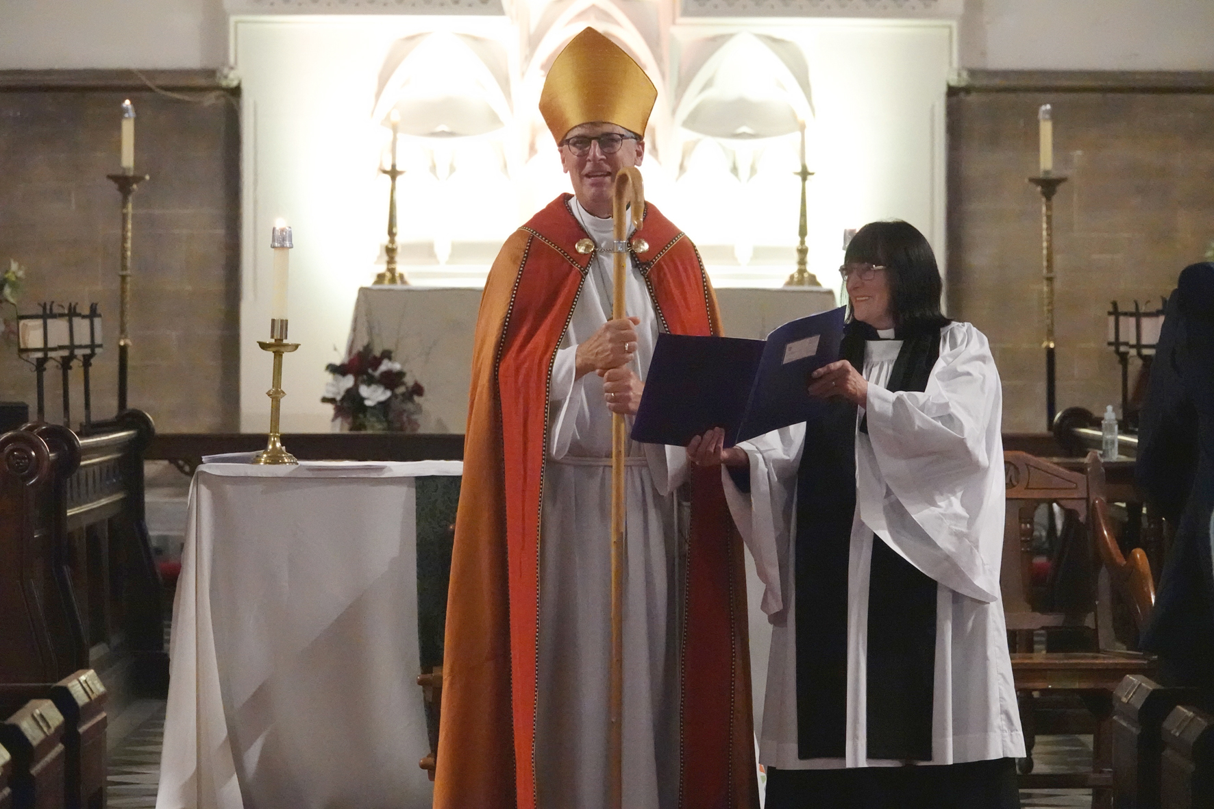 Bishop Martin standing at the front of St Stephen's, Redditch with his chaplain holding a book next to him