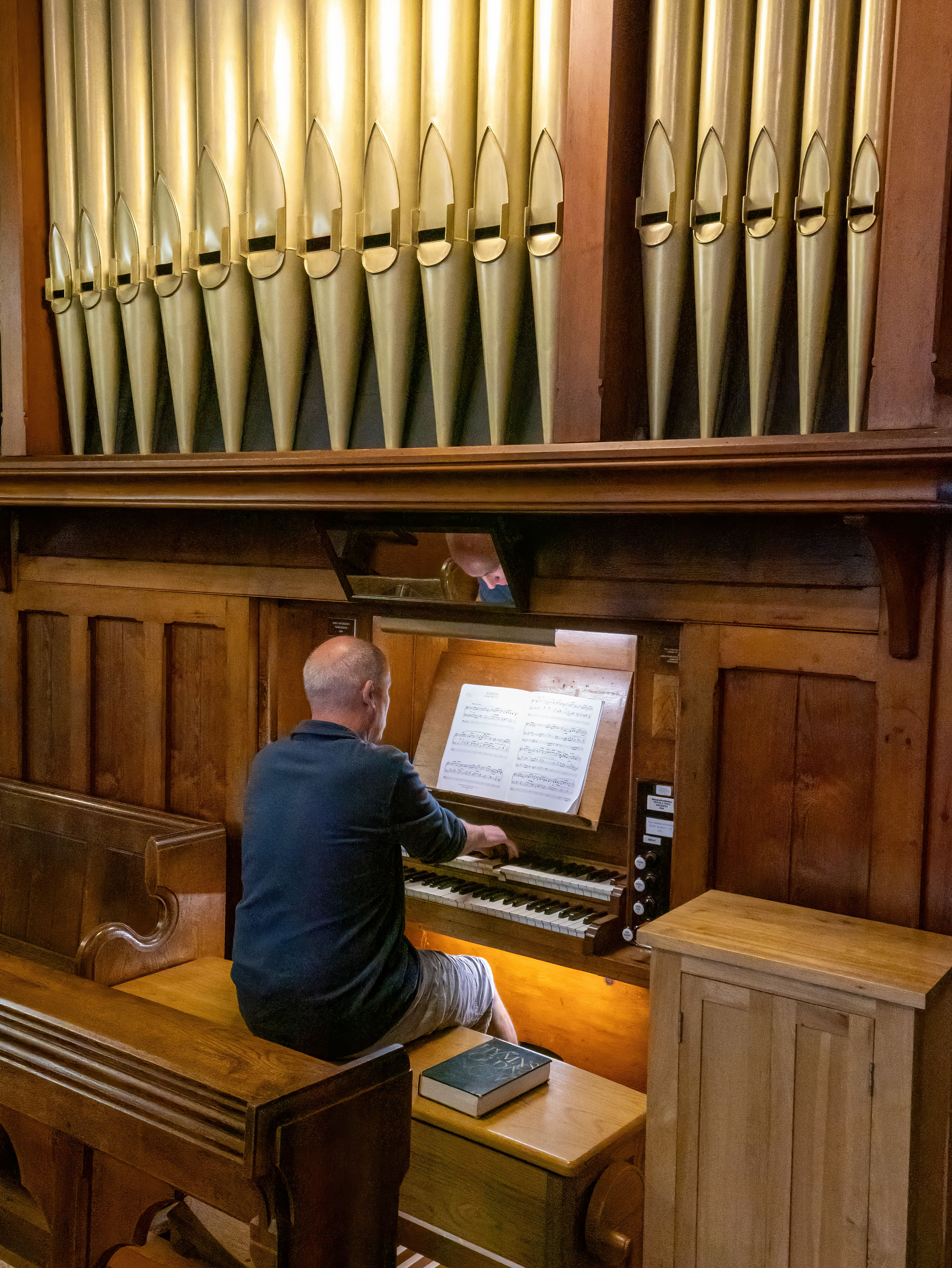 Man playing the organ with the pips above him