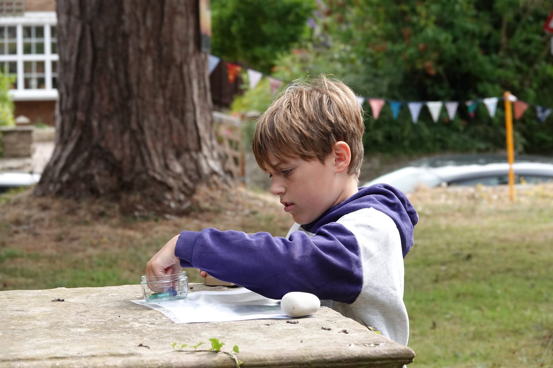 Boy takes a token out of a pot at a grave stone in Clifton churchyard