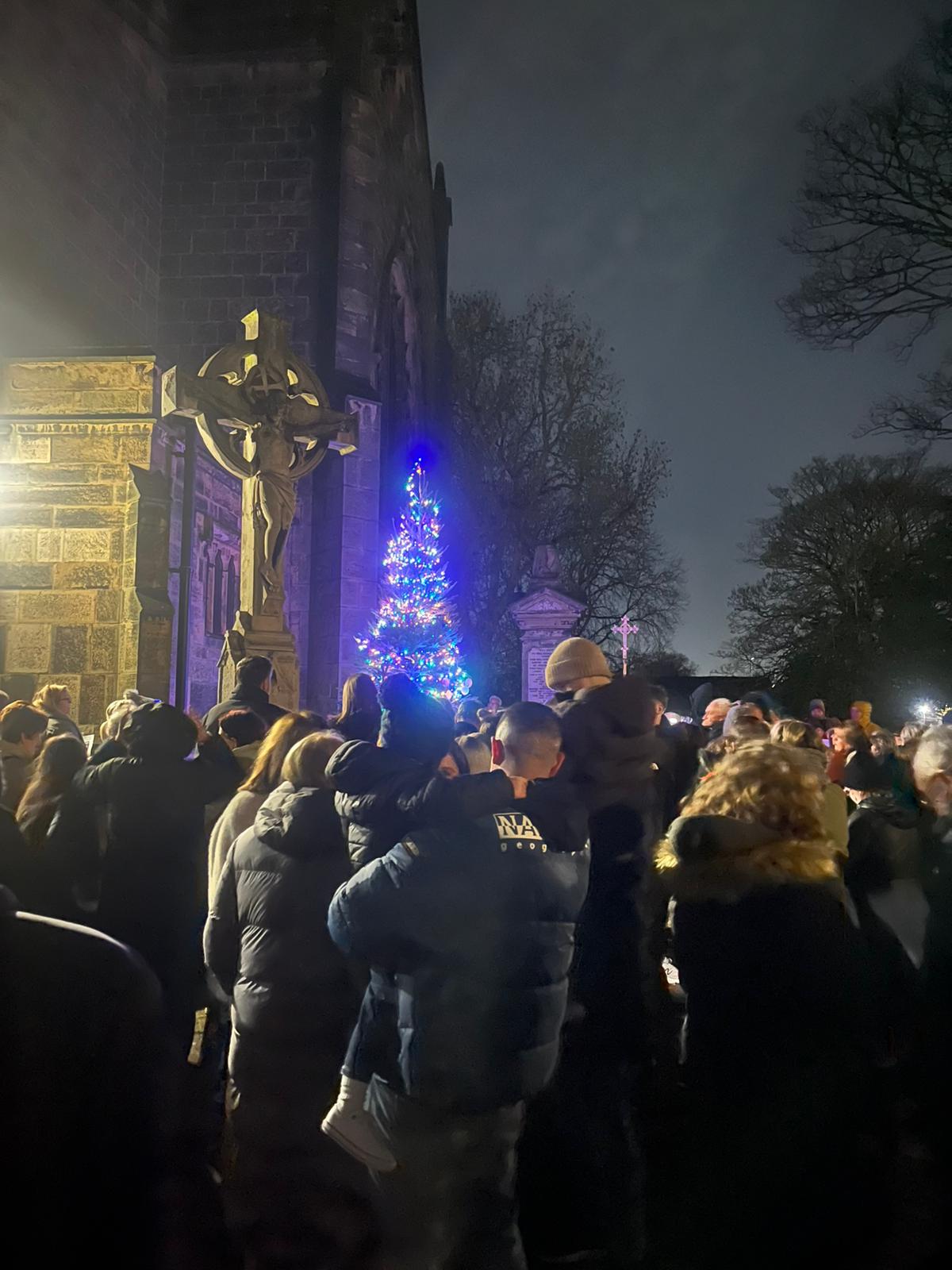 People gathered outside Christ Church in Coseley with a big Christmas tree lit up in front of them