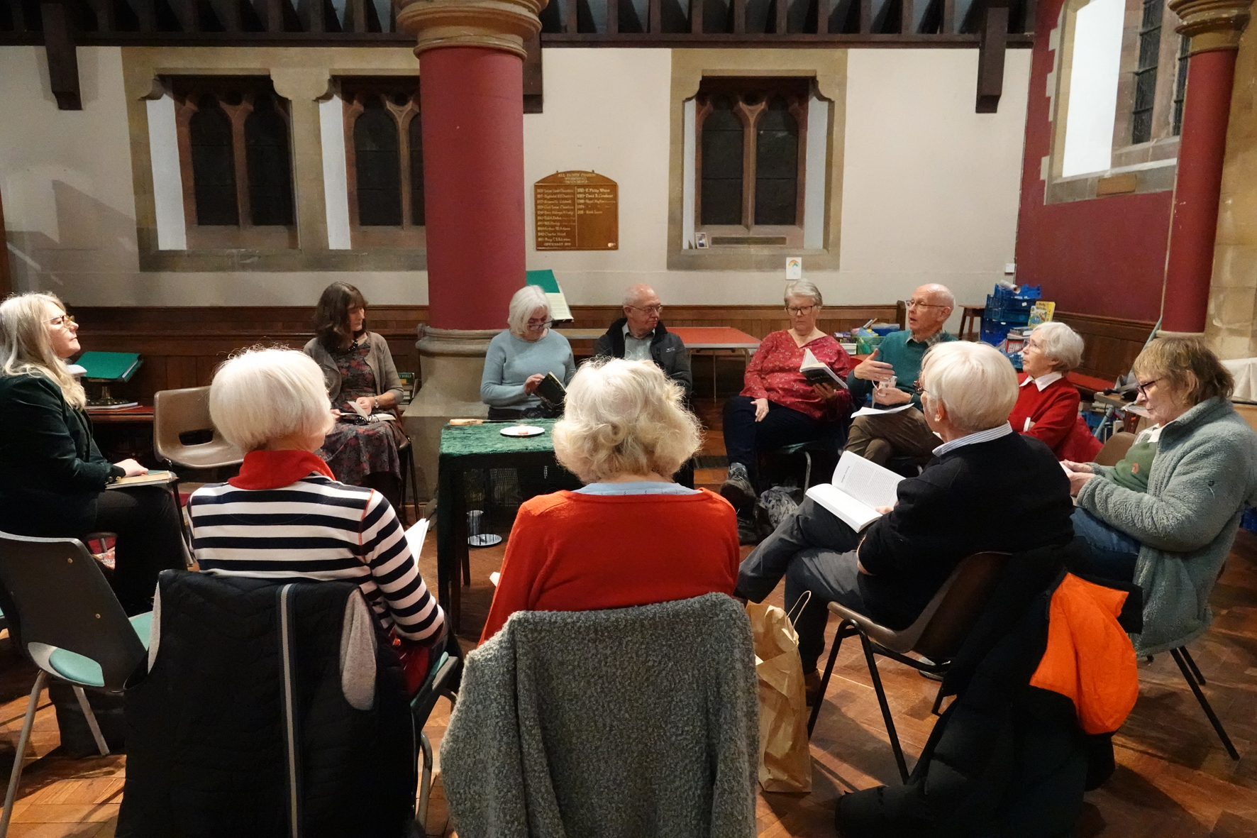 People sitting in a circle at the back of Wribbenhall church discussing a book.