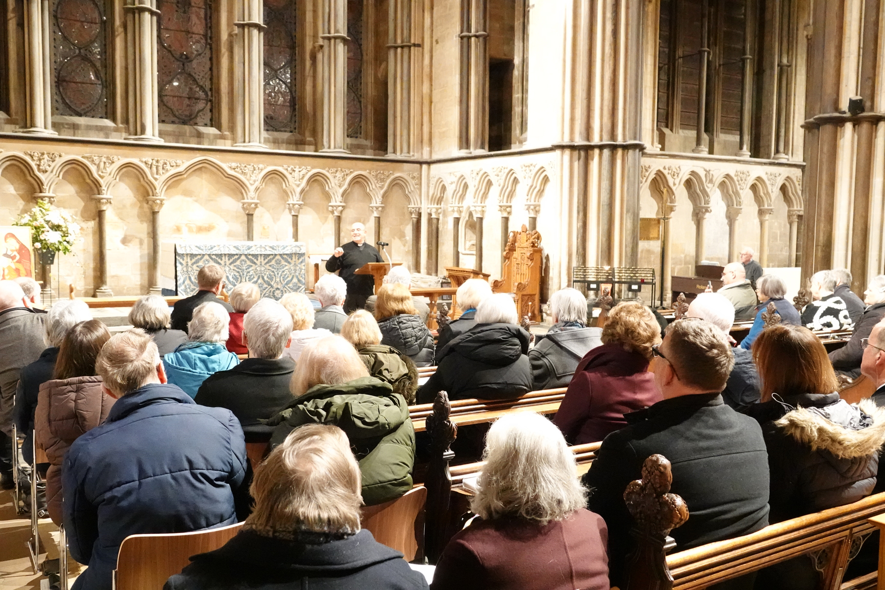 A picture from the back of the Lady Chapel in the cathedral with people sitting listening to Father Abusada stood at the front.