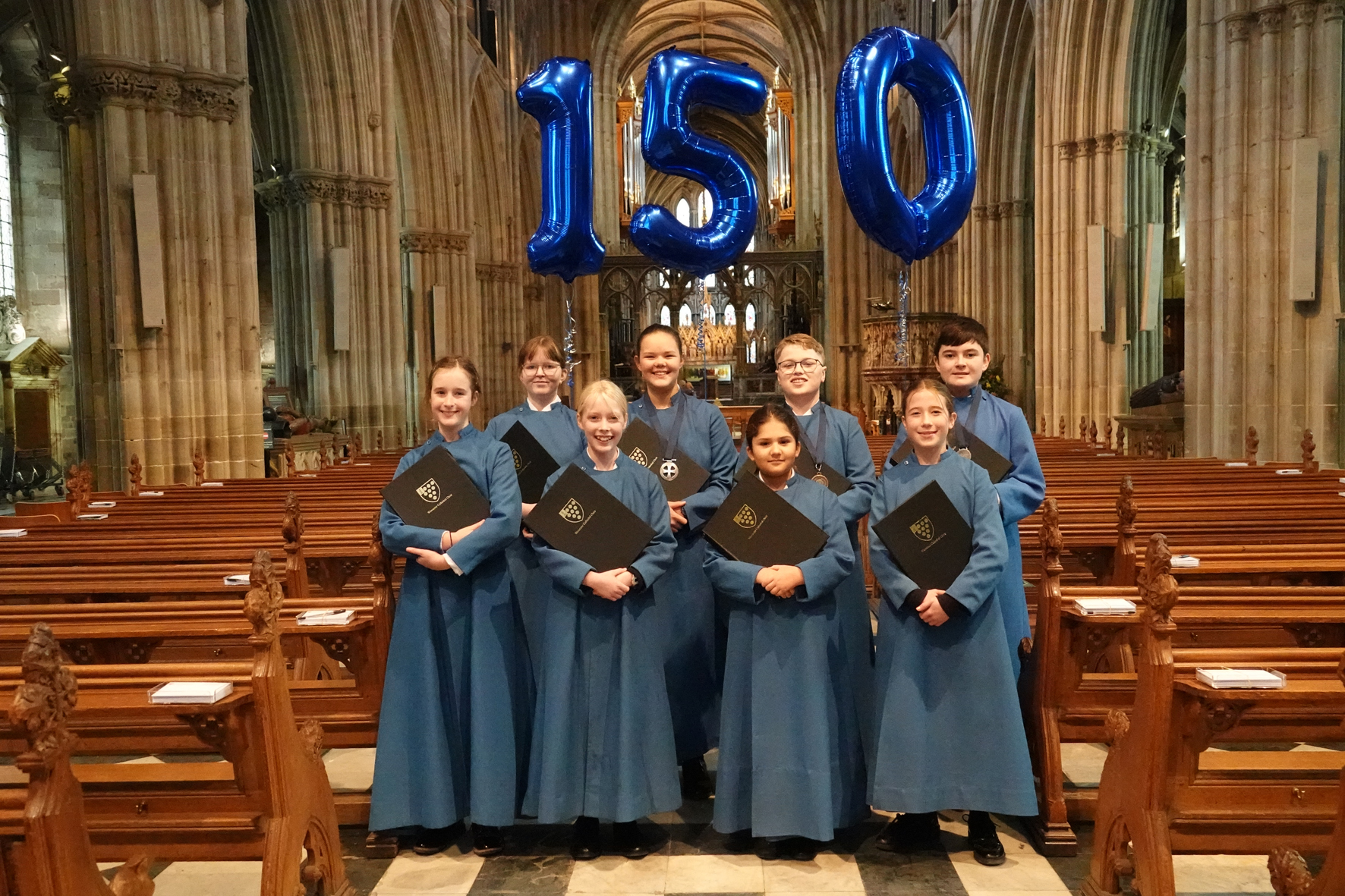 The cathedral voluntary choir in the cathedral nave with balloons saying '150' above them