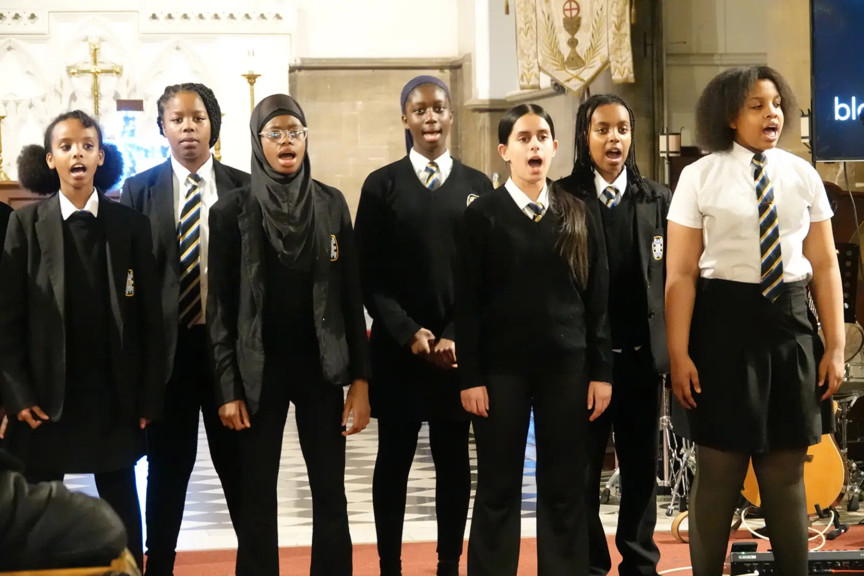 Seven girls from Broadway Academy school choir singing at the front of church