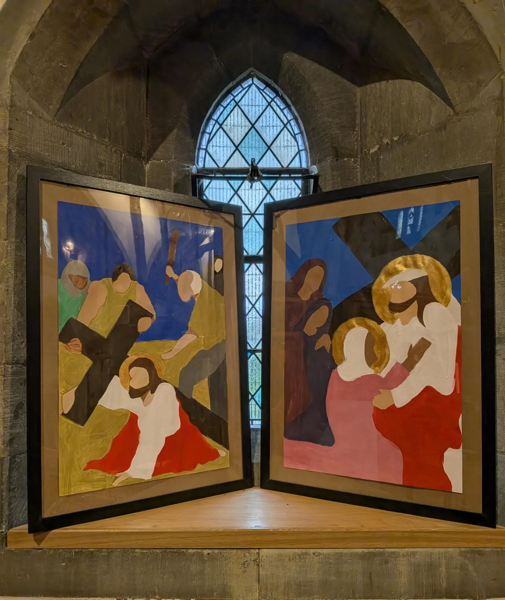 Two paintings of the Stations of the Cross in a window in a church