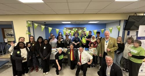 A group of people standing in front of a table in the Alexandra Hospital celebrating Mitzvah day